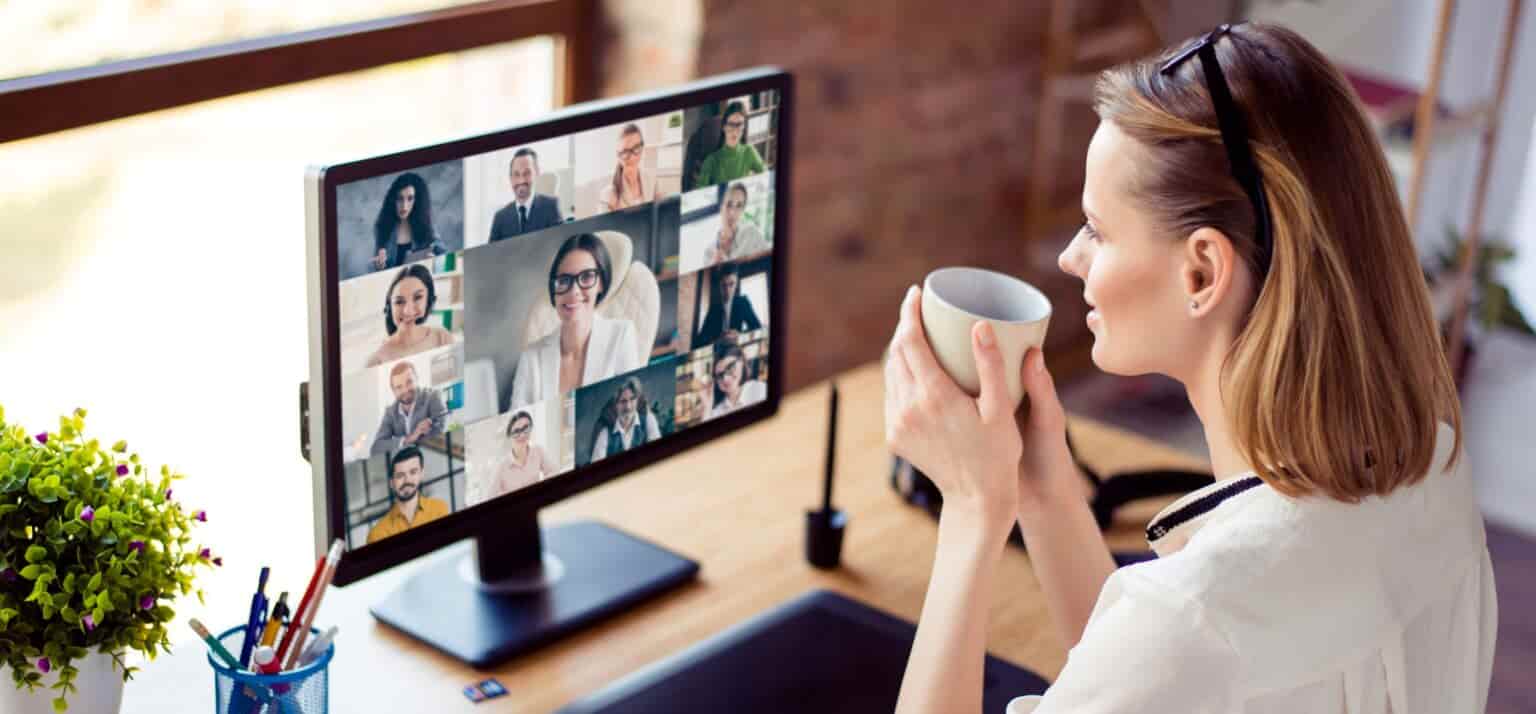 woman drinking from a mug while on a video conferencing call on a computer