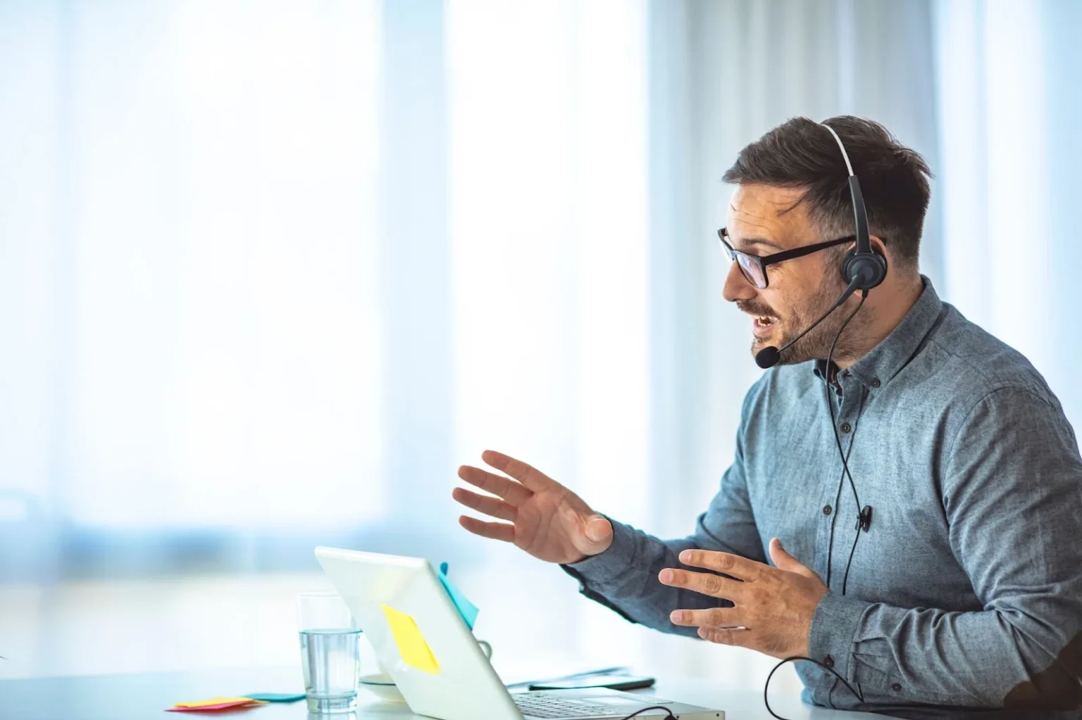 Male Tech support in headset consulting a client working in office